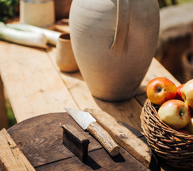 close up of a knife and a basket of red apples