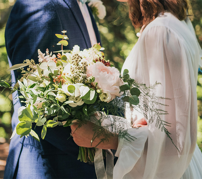 close up of a bouquet of flowers and a bride and groom hugging