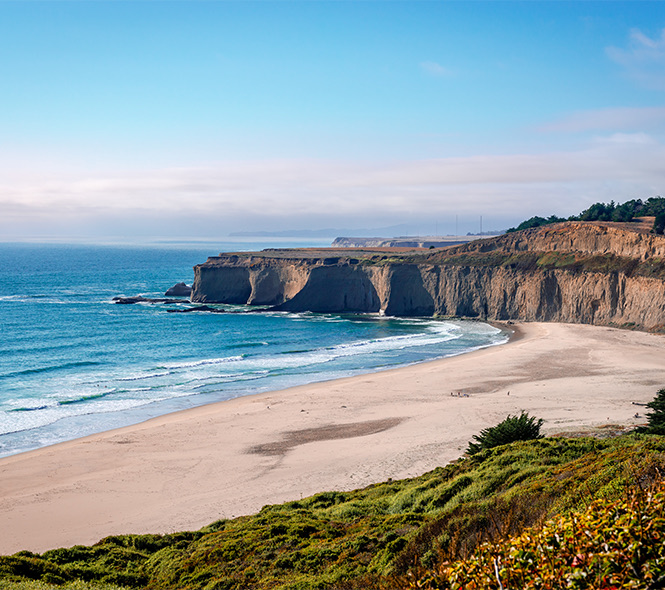the beach with rocky ledges along some of the shoreline