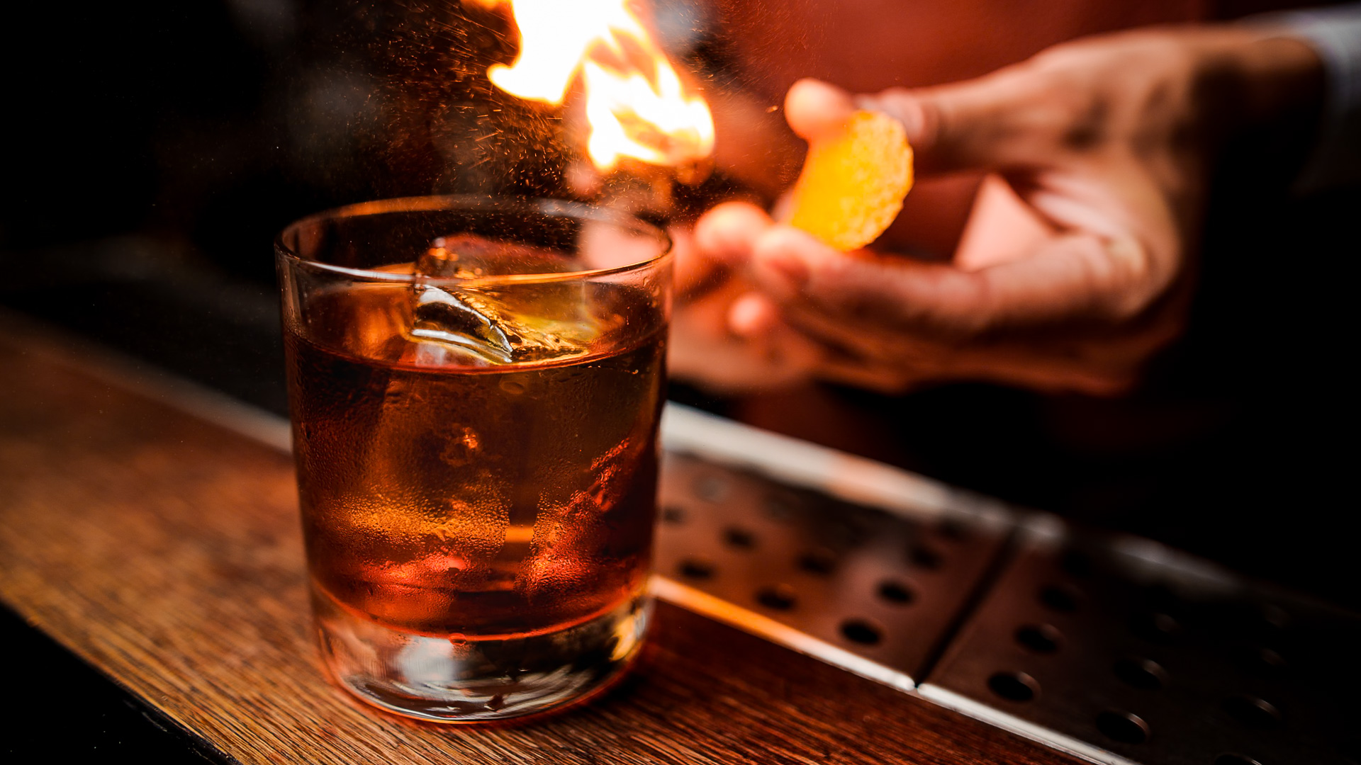 a hand holding a chip in front of a glass of alcohol with fire
