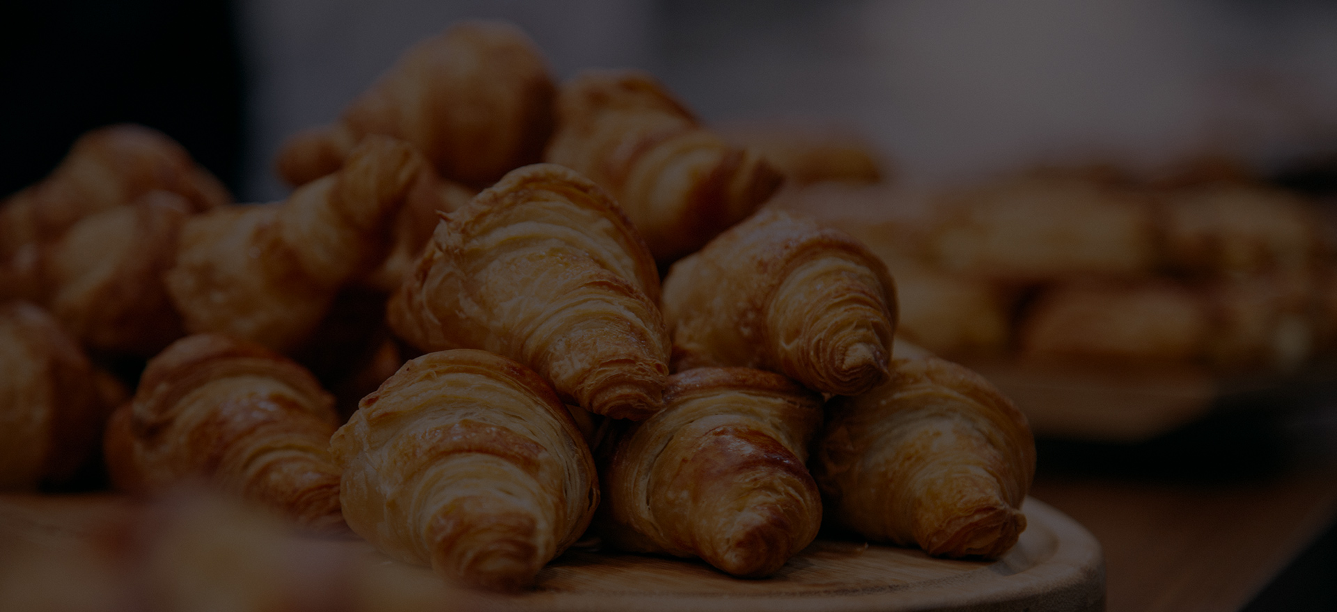 a pile of croissants on a wooden plate