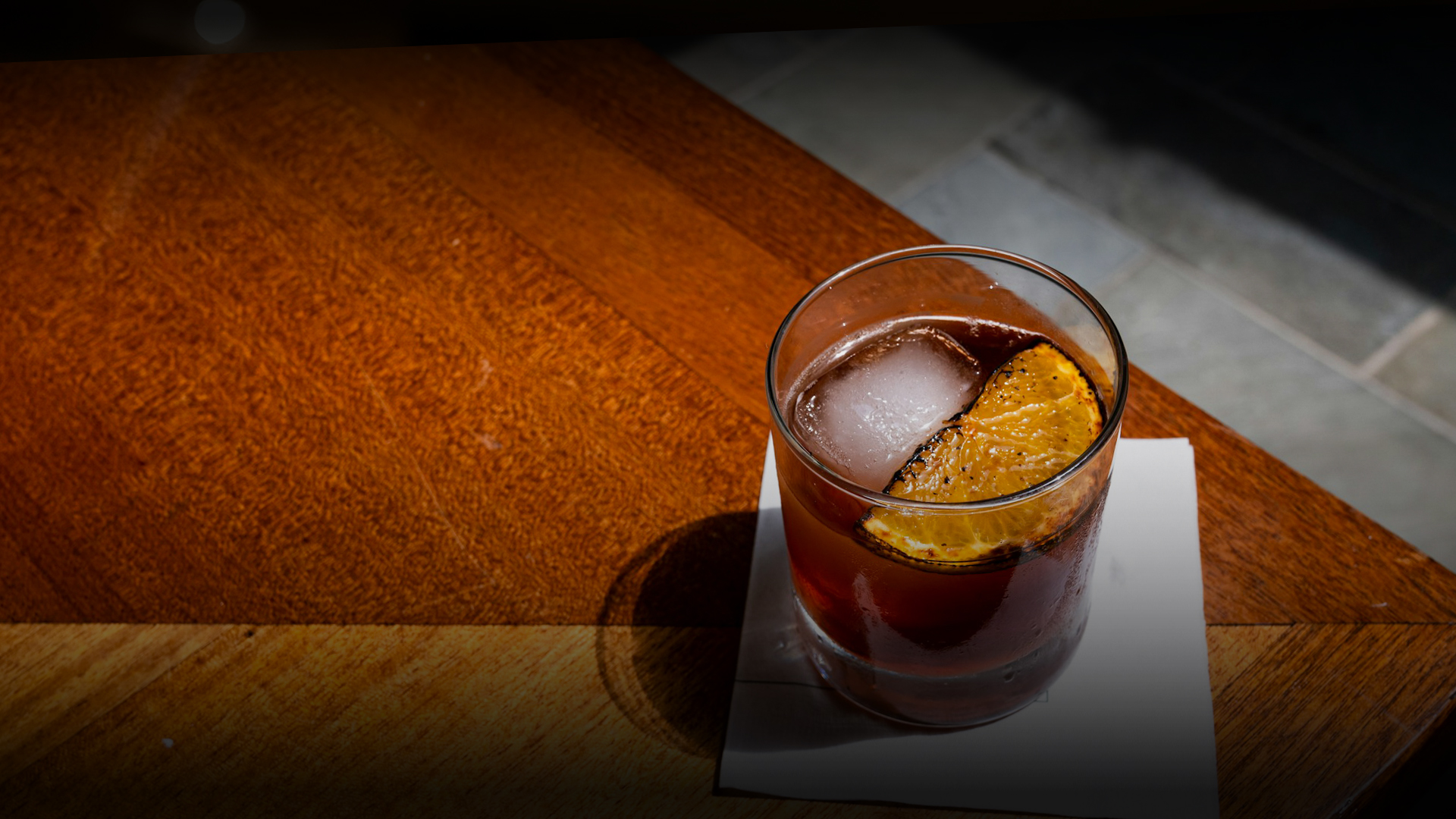 a glass of liquid with ice and a slice of orange on top