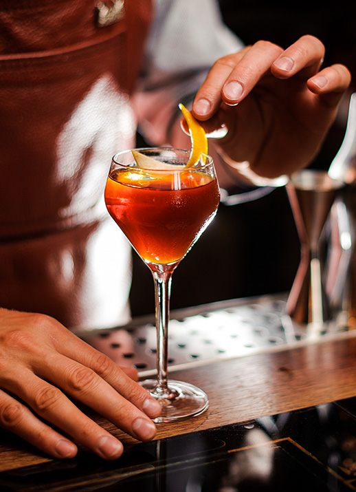 a person adding a slice of orange to a drink