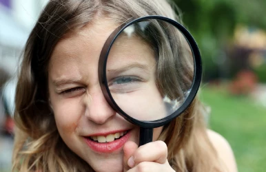 a girl holding a magnifying glass over her eye