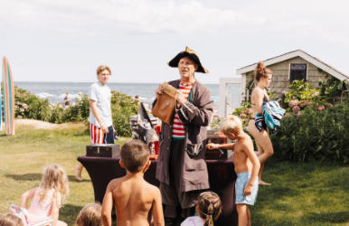 a man in a pirate garment standing in front of a group of children