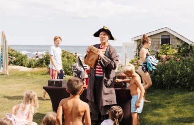a man in a pirate garment standing in front of a group of children