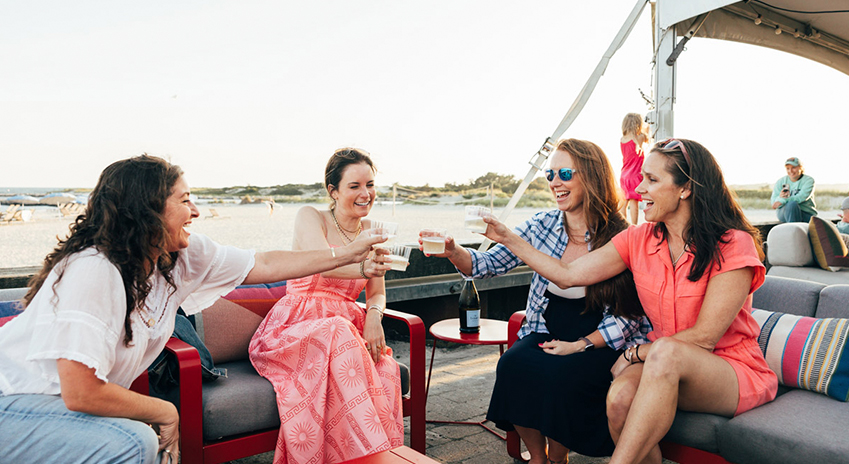 a group of women sitting on a boat and drinking