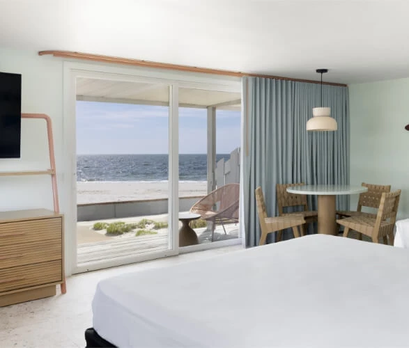 a bedroom with a table and chairs and a door to the ocean