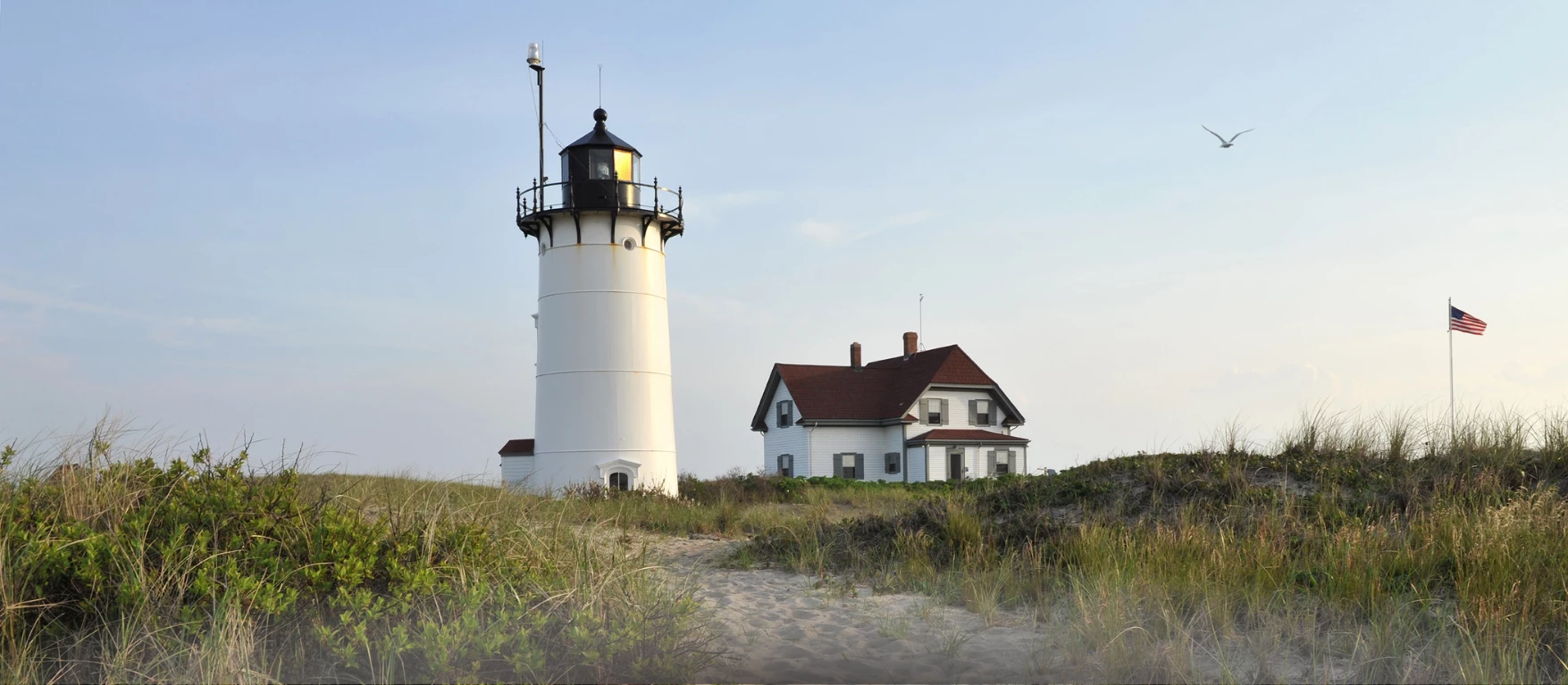 a white lighthouse next to a house in cape cod