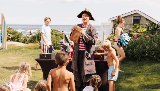 a man in a pirate garment standing in front of a group of children