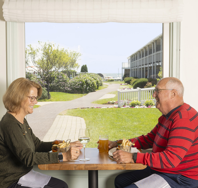a man and woman sitting at a table with food and drinks