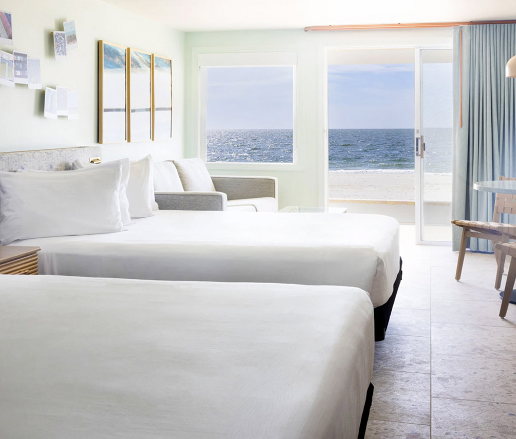 a room with two beds and a beach view