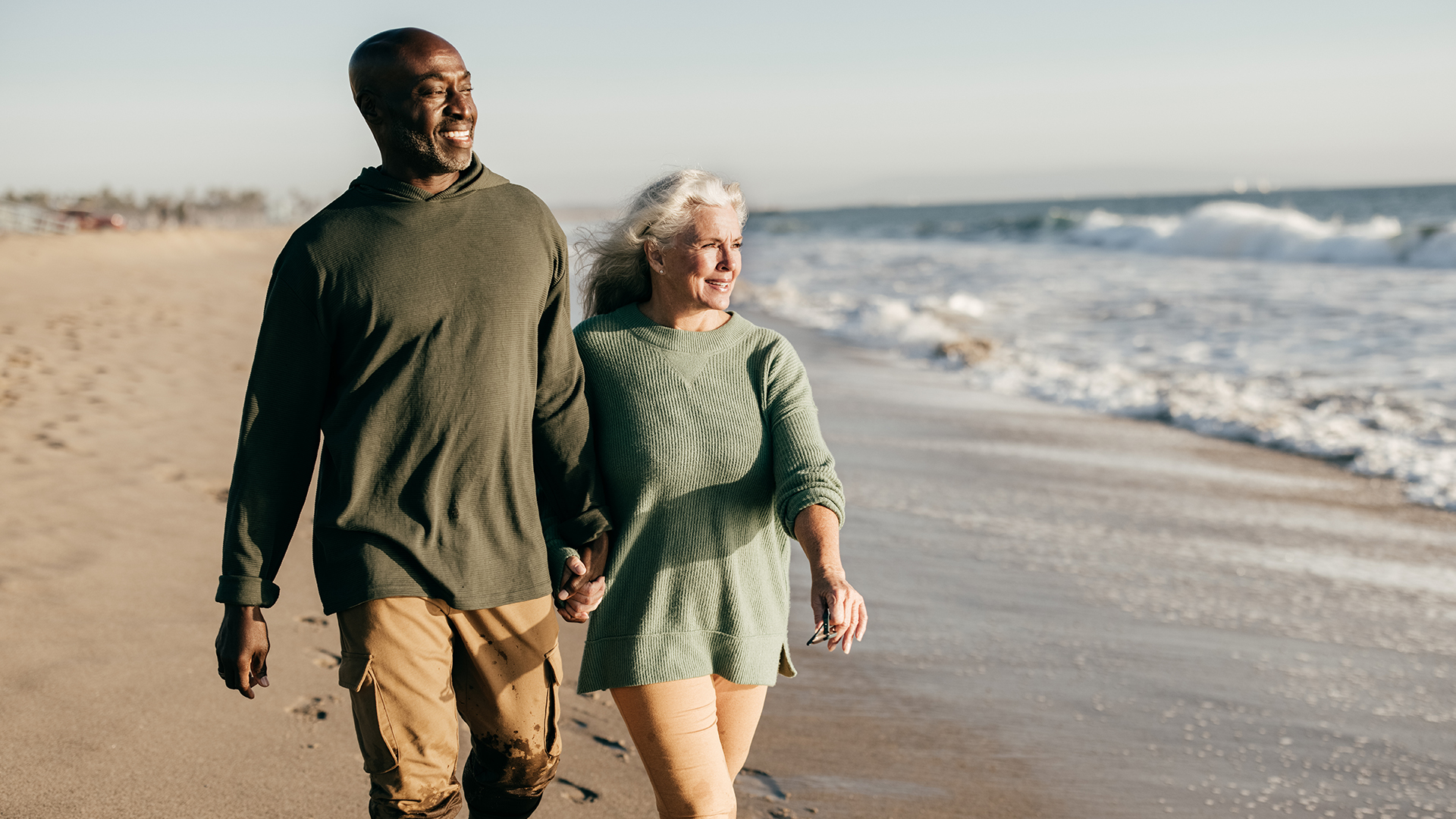 a man and woman holding hands on a beach