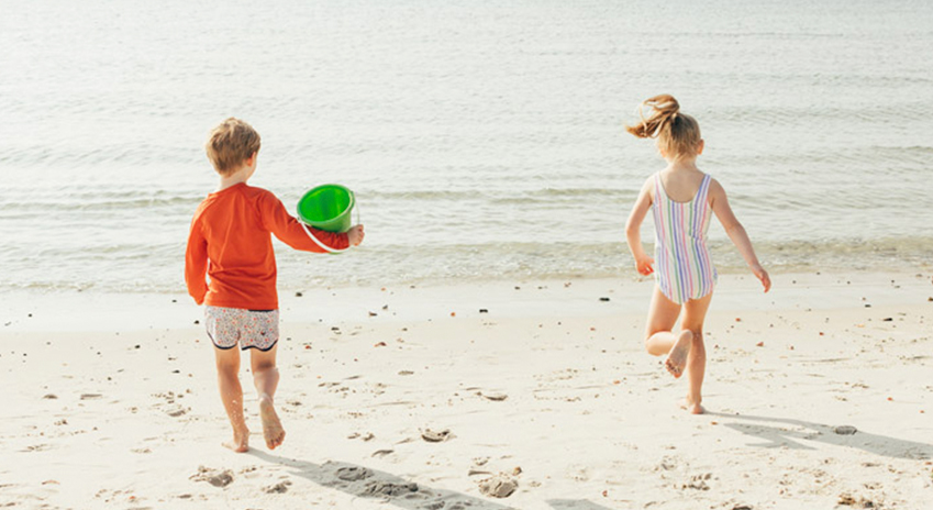 a boy and girl running on a beach