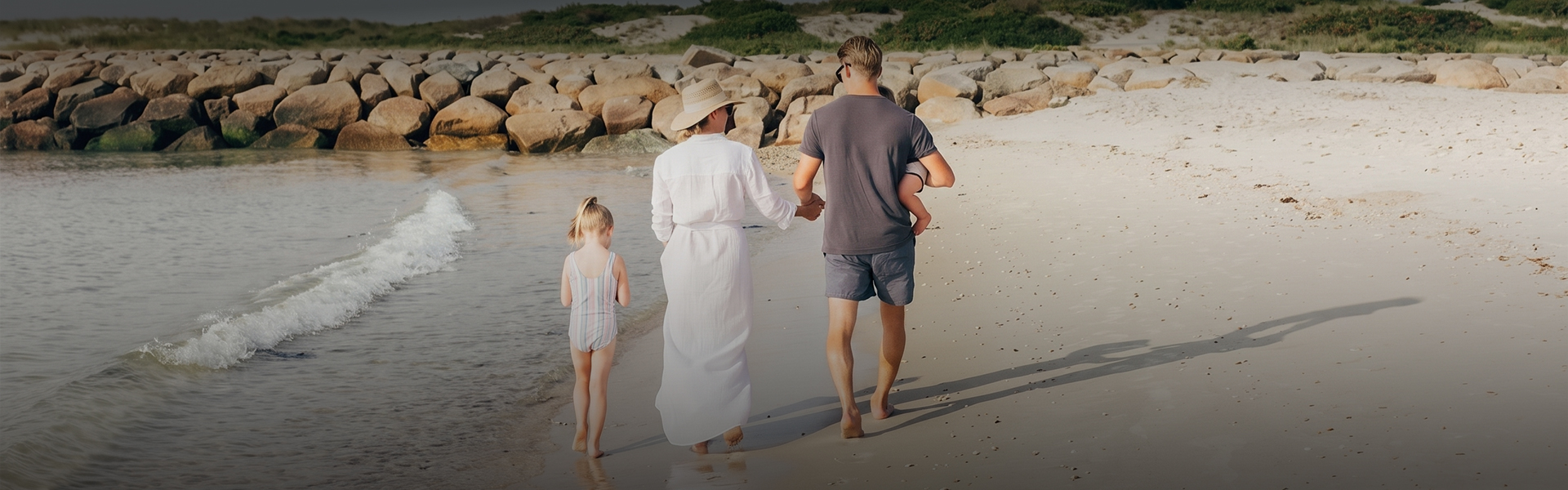 a man and woman holding hands and walking on a beach