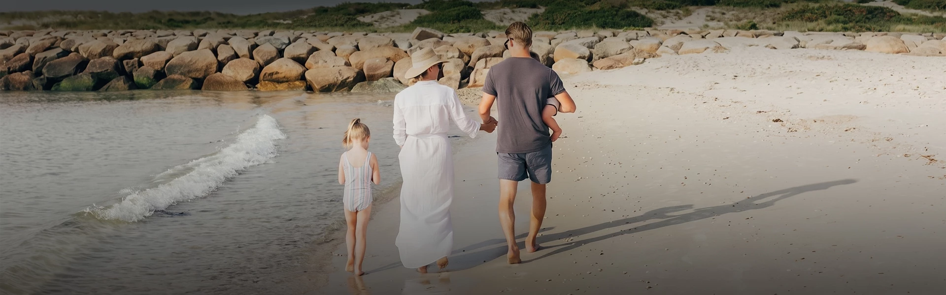 a man and woman holding hands and walking on a beach