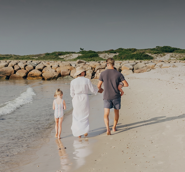a man and woman holding hands and walking on a beach