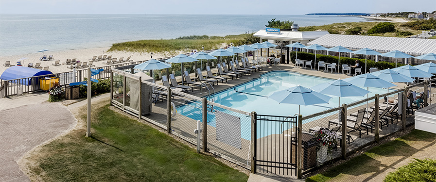 a pool with umbrellas and chairs on a beach