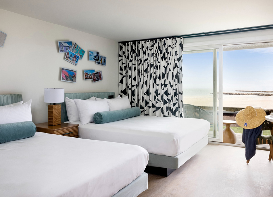 a room with two beds and a balcony overlooking the ocean