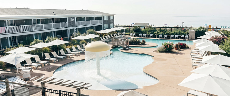 a pool with a fountain and umbrellas