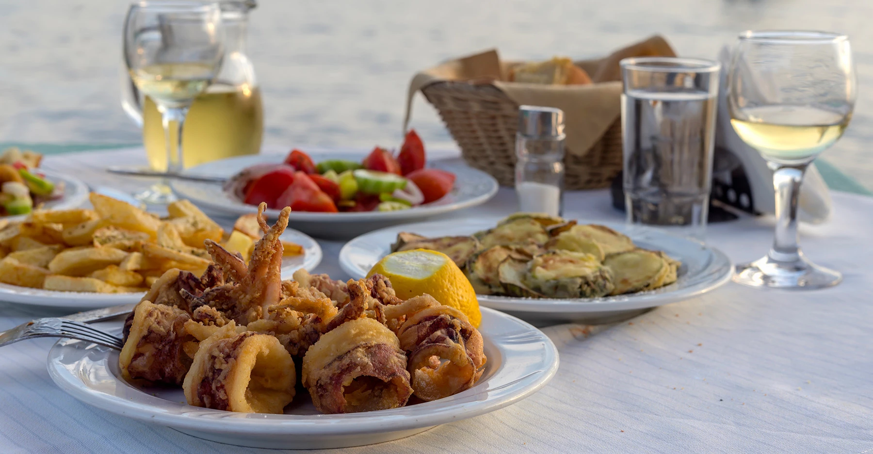 a table with plates of food and glasses of wine