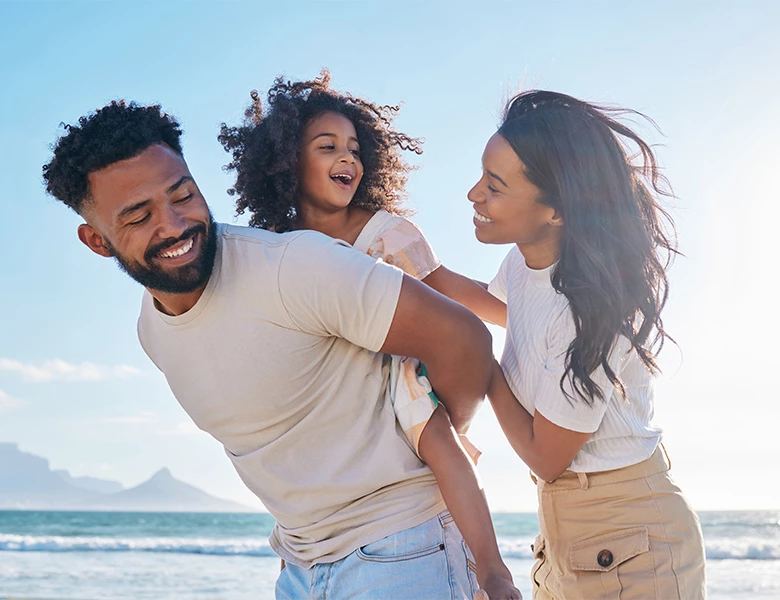 a man and woman holding a child on the beach