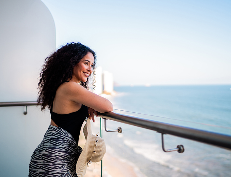 a woman leaning on a railing looking out to the ocean