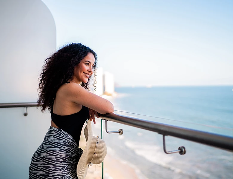 a woman leaning on a railing looking out to the ocean
