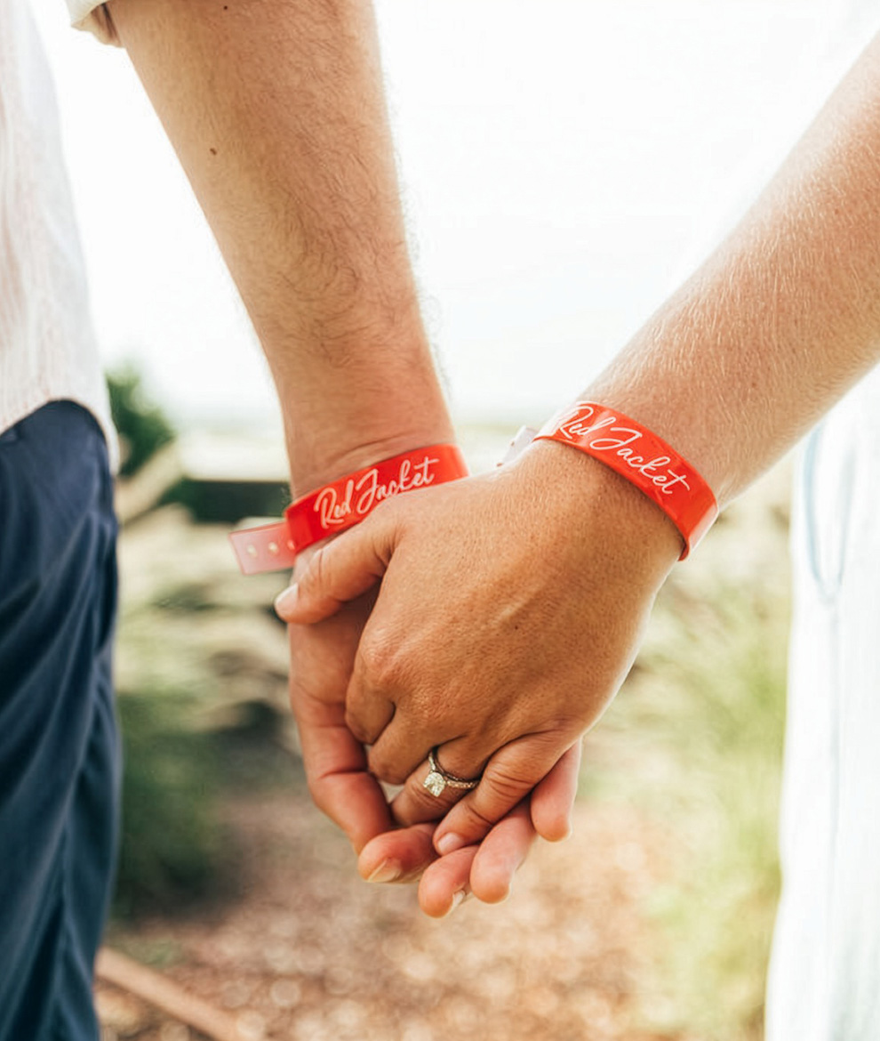 a couple holding hands with red bracelets
