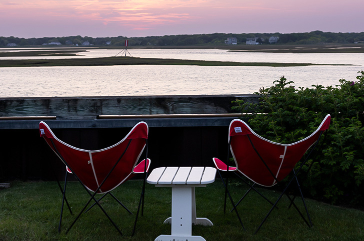 a table and chairs on grass by water