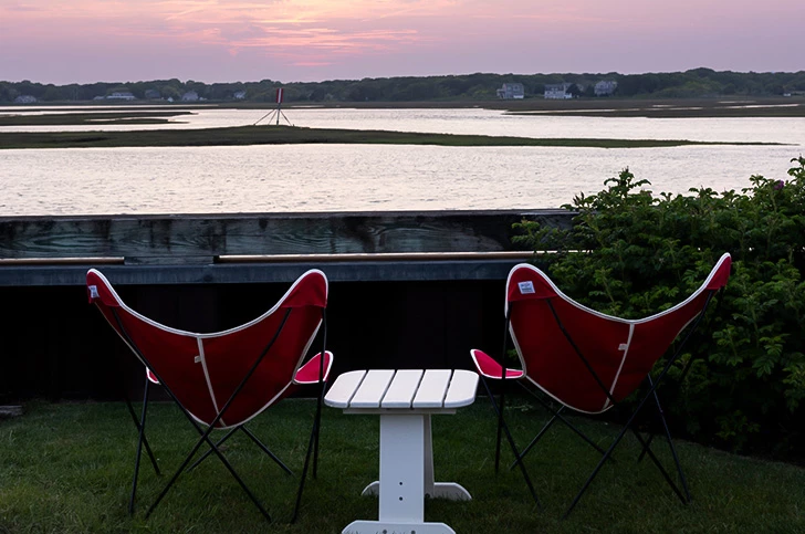 a table and chairs on grass by water