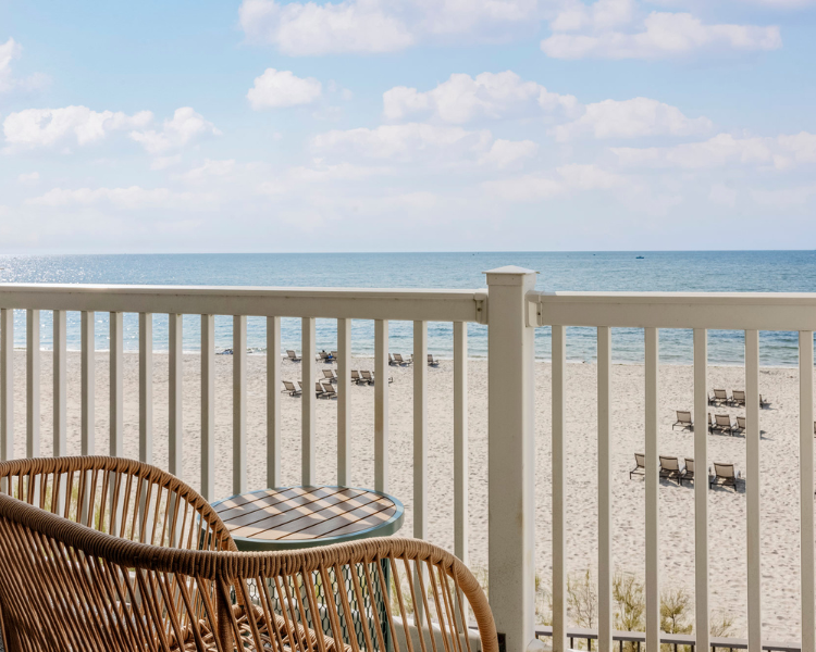 a chair and table on a balcony overlooking a beach
