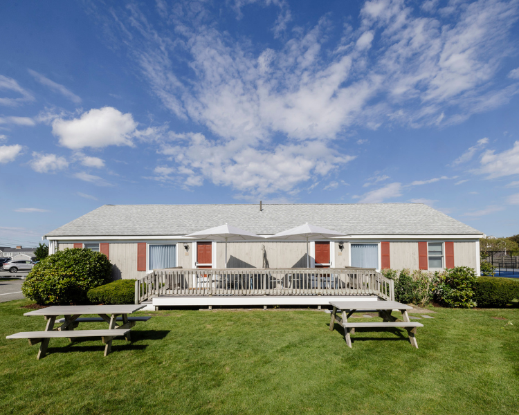 a house with a deck and picnic tables