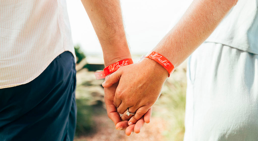 a couple holding hands with red wristbands