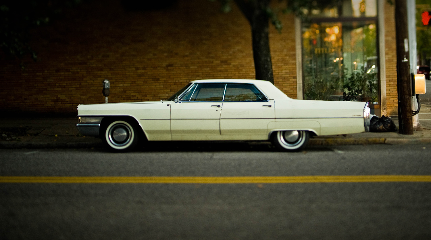 a light yellow vintage car parked on the street