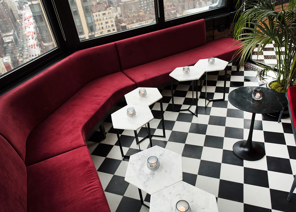 a red couch with white marble tables and candles