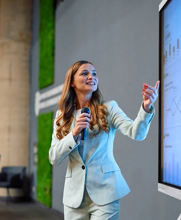 a woman in a suit pointing at a screen
