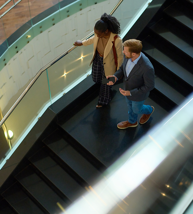 a man and woman walking down a black staircase