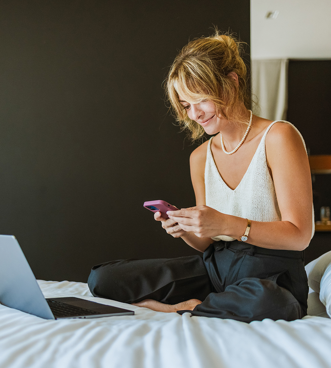 a woman sitting on a bed looking at a phone