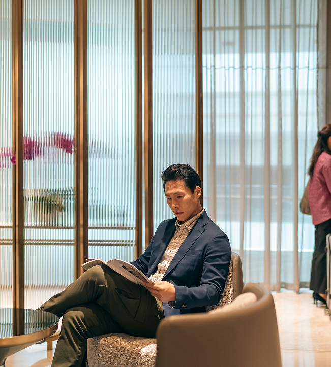 a man sitting in a chair reading a magazine