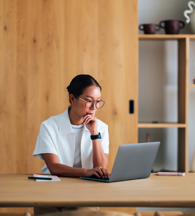 a woman sitting at a desk with her hand on her chin