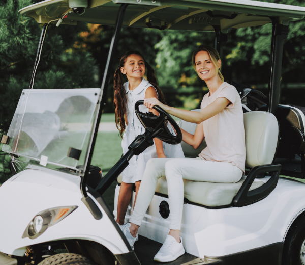 a woman and a girl in a golf cart