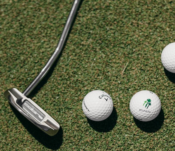 golf balls and a golf club on a green surface
