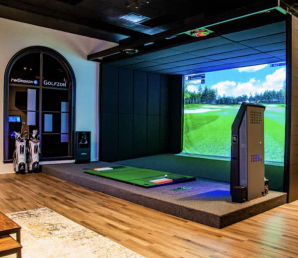 a room with a large screen and golf equipment