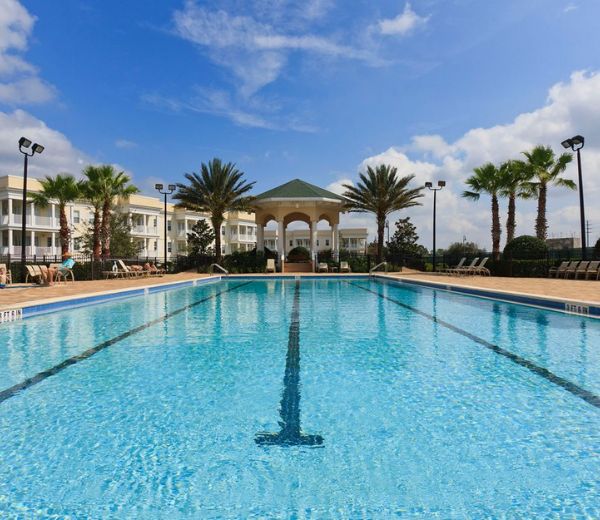 A large outdoor pool with a gazebo and palm trees in the background.