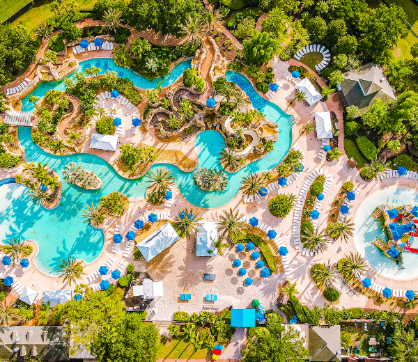 An aerial view of a large pool area with a water slide and lounge chairs.