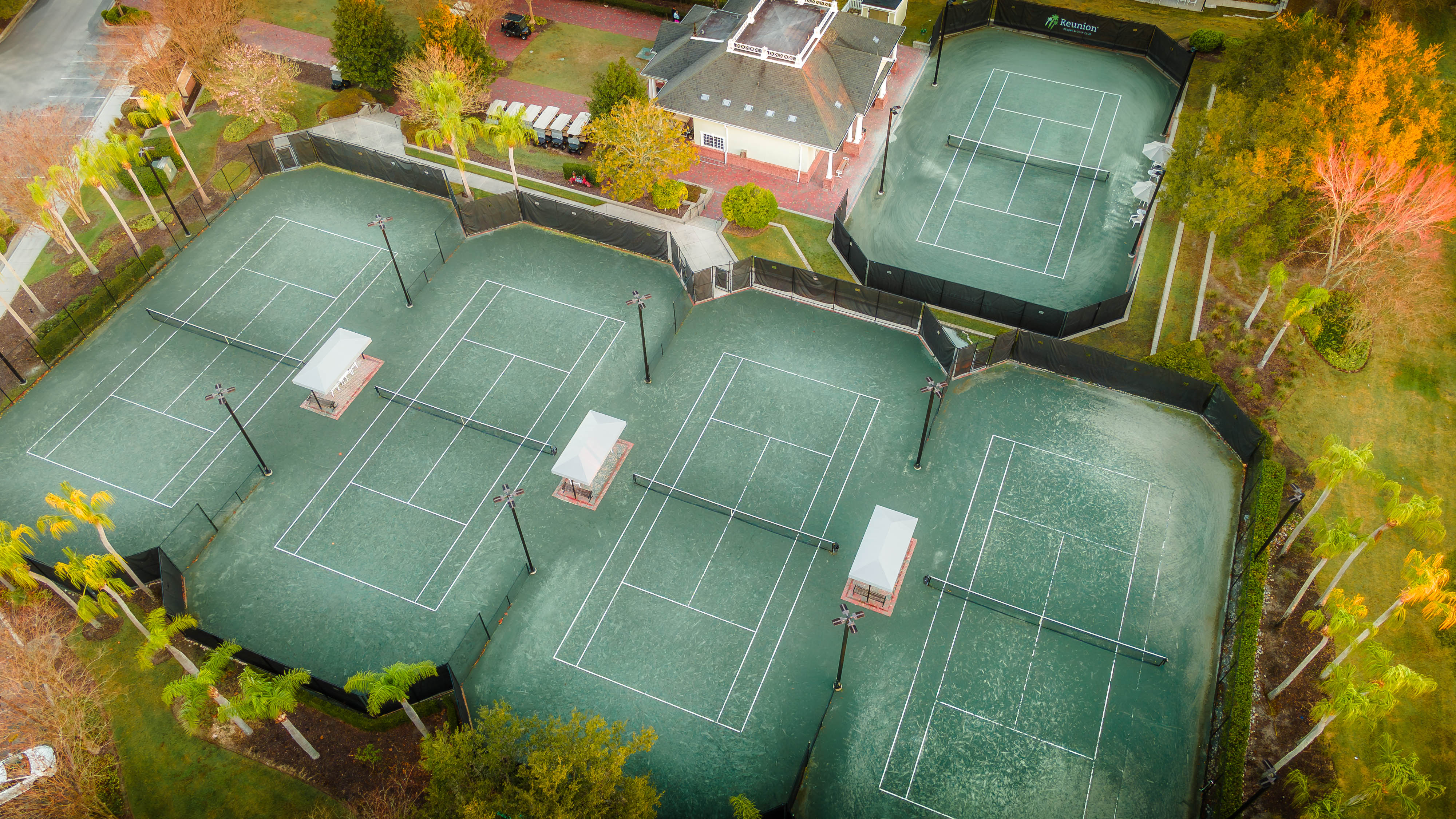 a tennis courts with white lines and a house in the background
