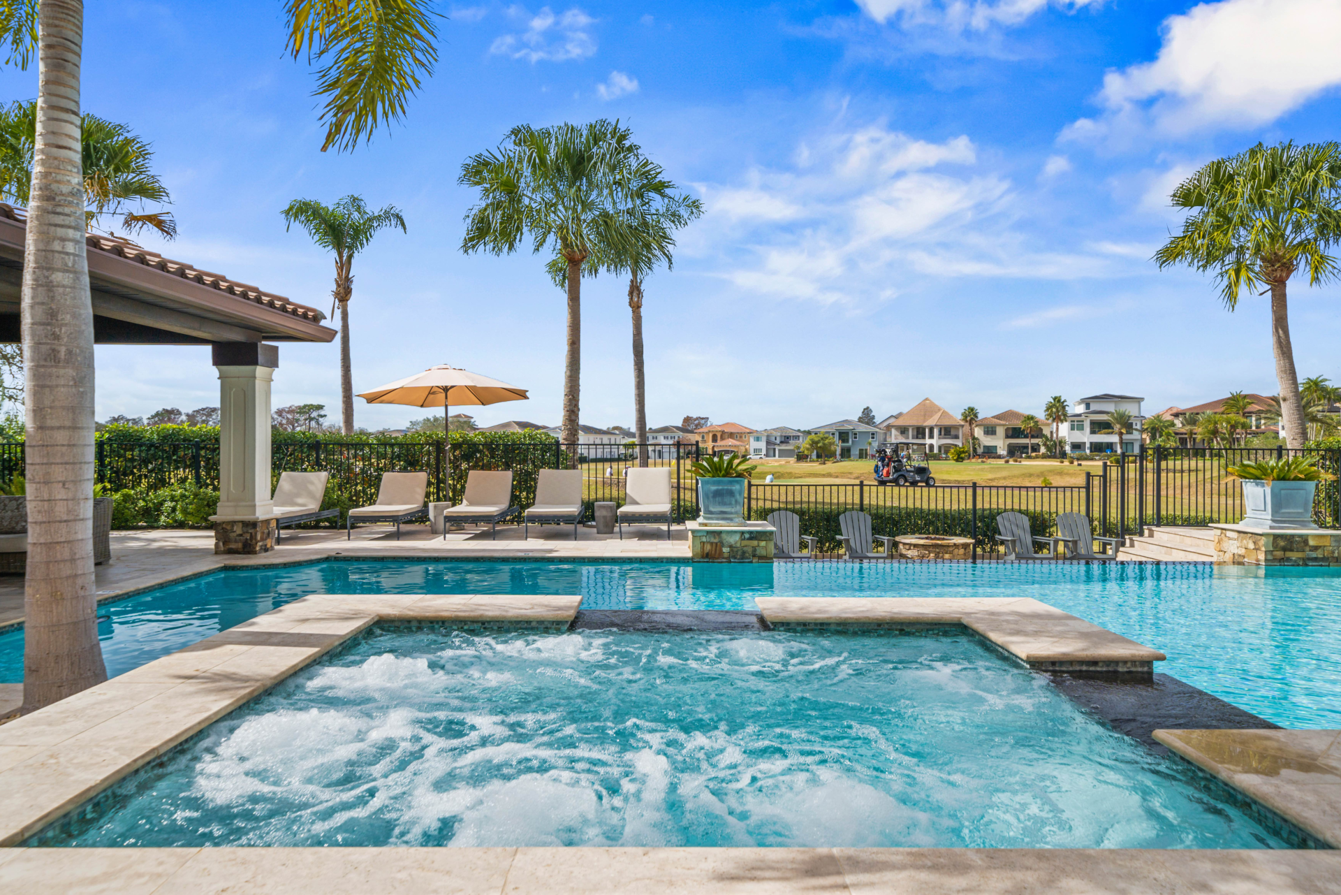 A resort pool with a jacuzzi and lounge chairs.