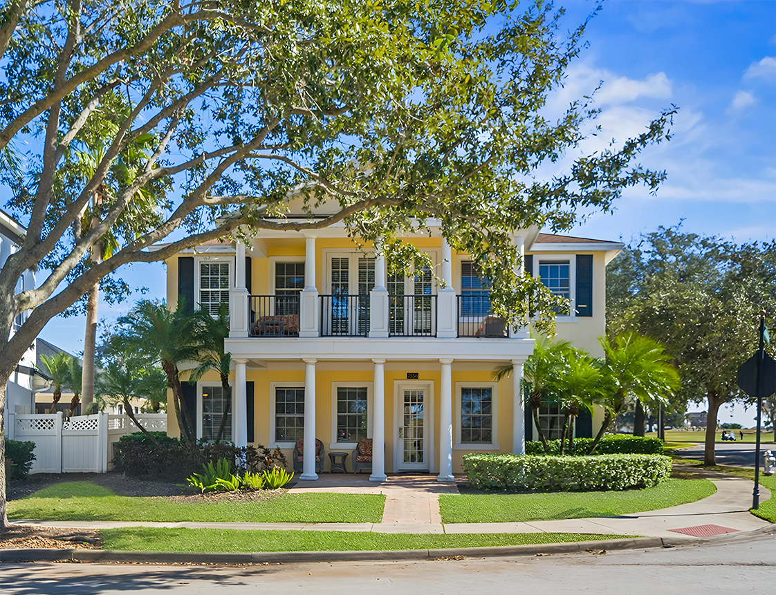 A two-story house with a yellow exterior and white columns