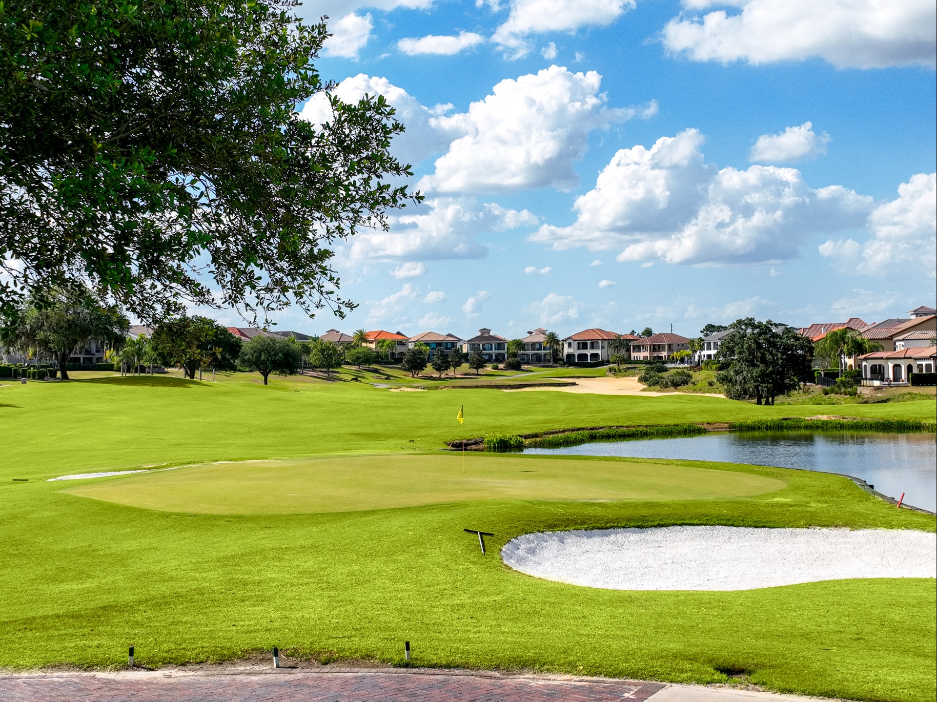 a golf course with a pond and houses in the background